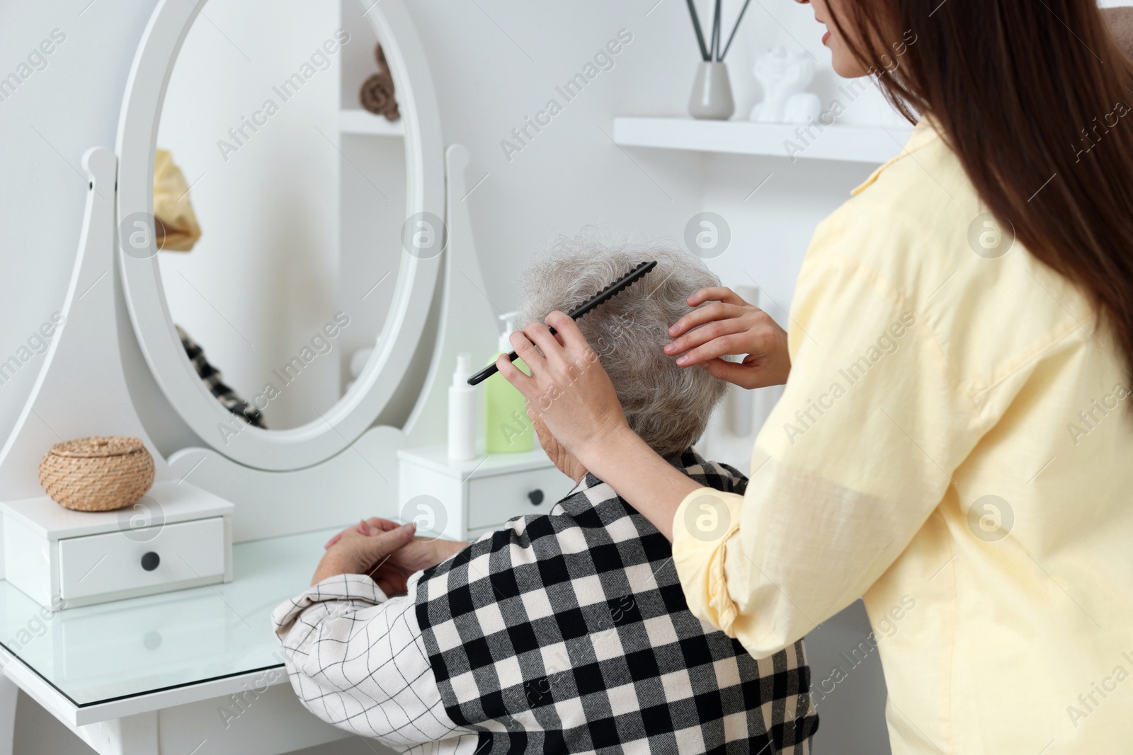 Photo of Woman brushing senior lady with comb indoors, closeup