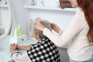 Photo of Granddaughter brushing her grandmother with brush at home, closeup