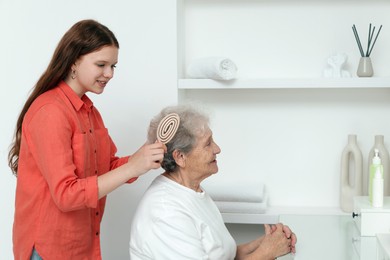 Photo of Granddaughter brushing her grandmother with brush at home