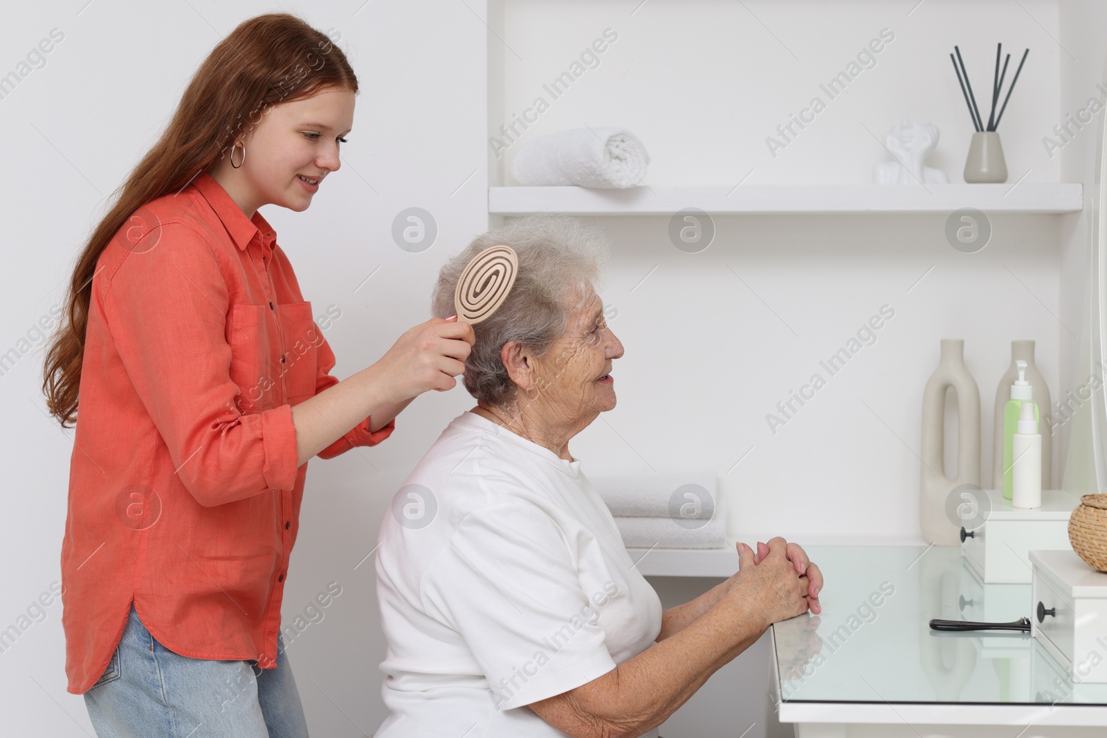 Photo of Granddaughter brushing her grandmother with brush at home