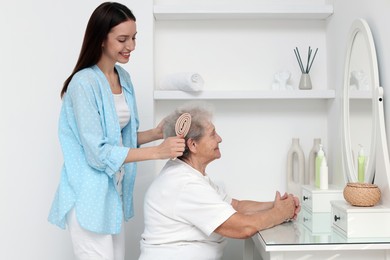 Photo of Woman brushing senior lady with brush indoors