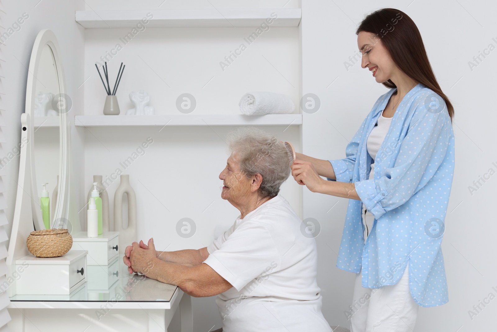 Photo of Woman brushing senior lady with brush indoors