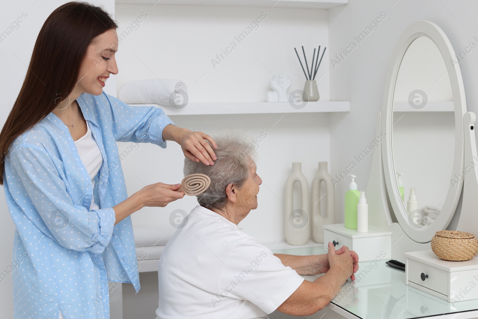 Photo of Woman brushing senior lady with brush indoors