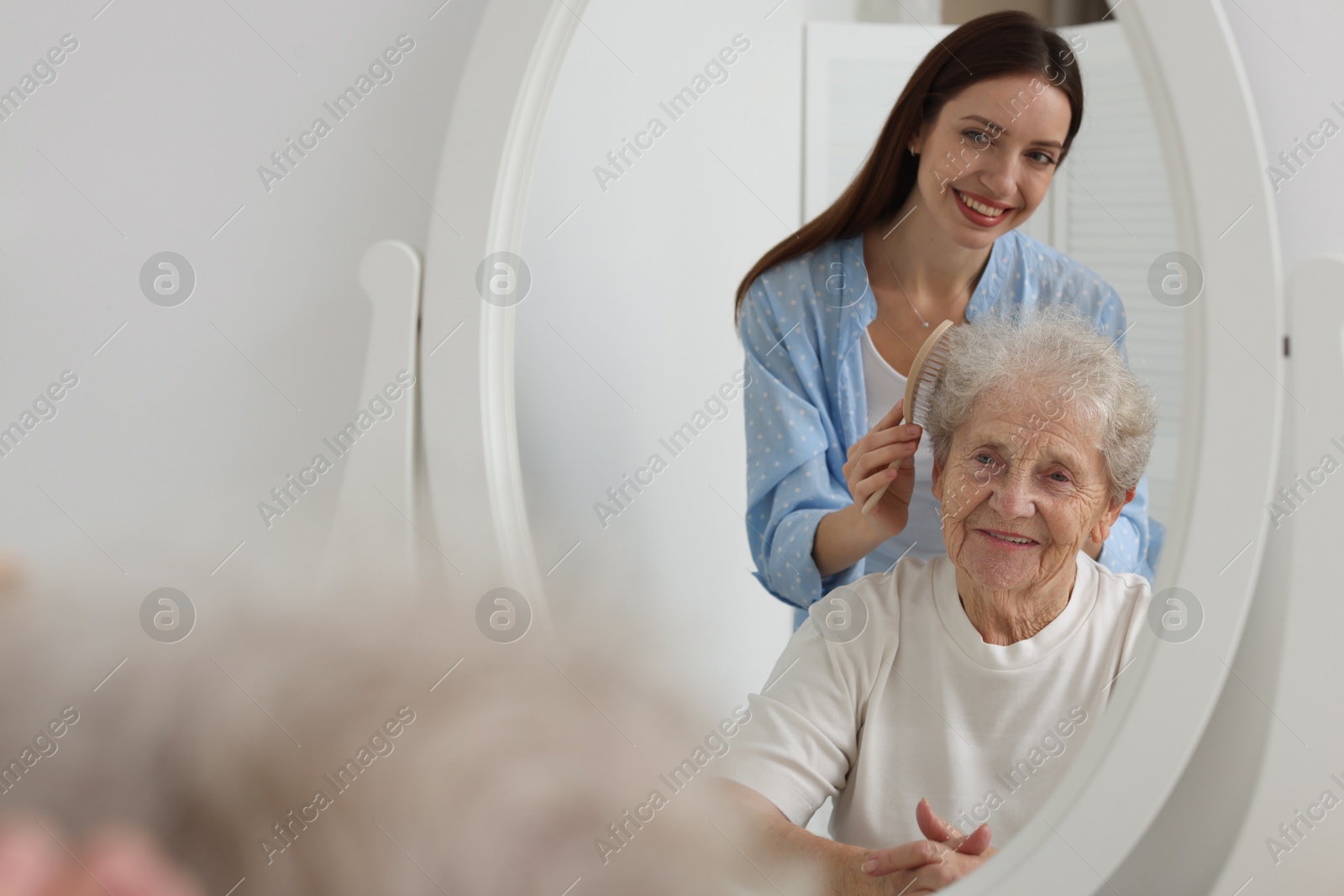 Photo of Woman brushing senior lady with brush indoors