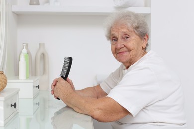 Photo of Senior woman with comb at dressing table indoors