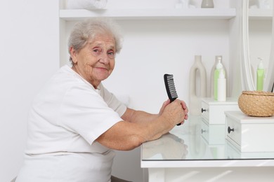 Photo of Senior woman with comb at dressing table indoors