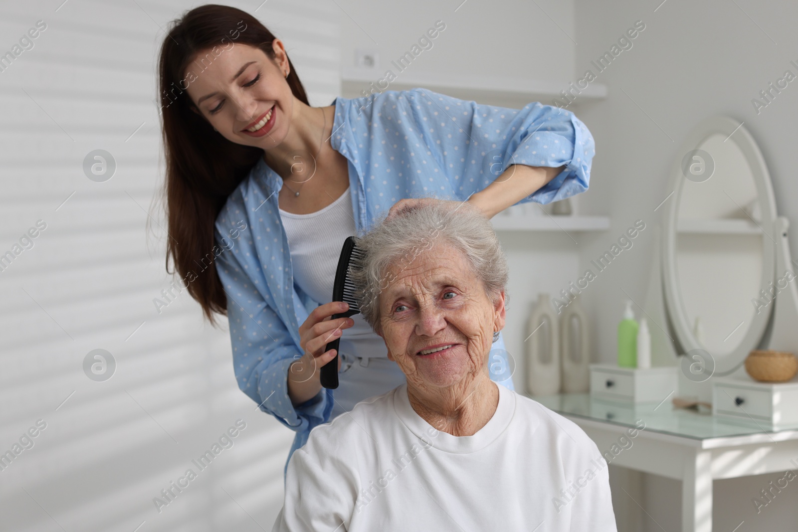 Photo of Beautiful woman brushing senior lady at home