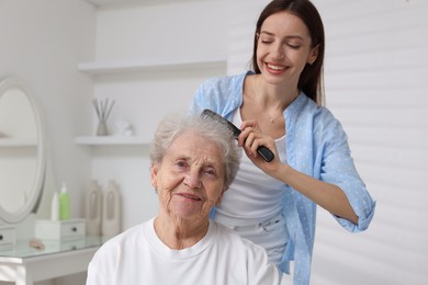 Photo of Beautiful woman brushing senior lady at home