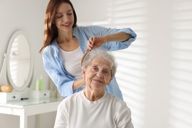 Photo of Beautiful woman brushing senior lady at home