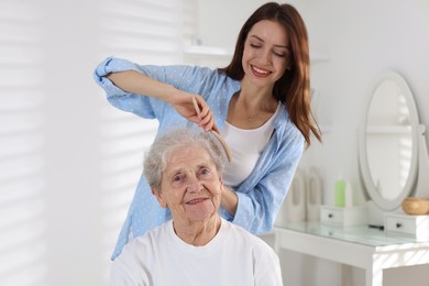 Photo of Beautiful woman brushing senior lady at home