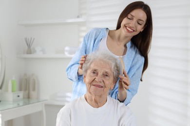 Photo of Beautiful woman brushing senior lady at home