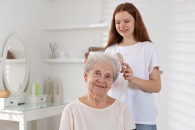 Photo of Granddaughter brushing her grandmother with brush at home