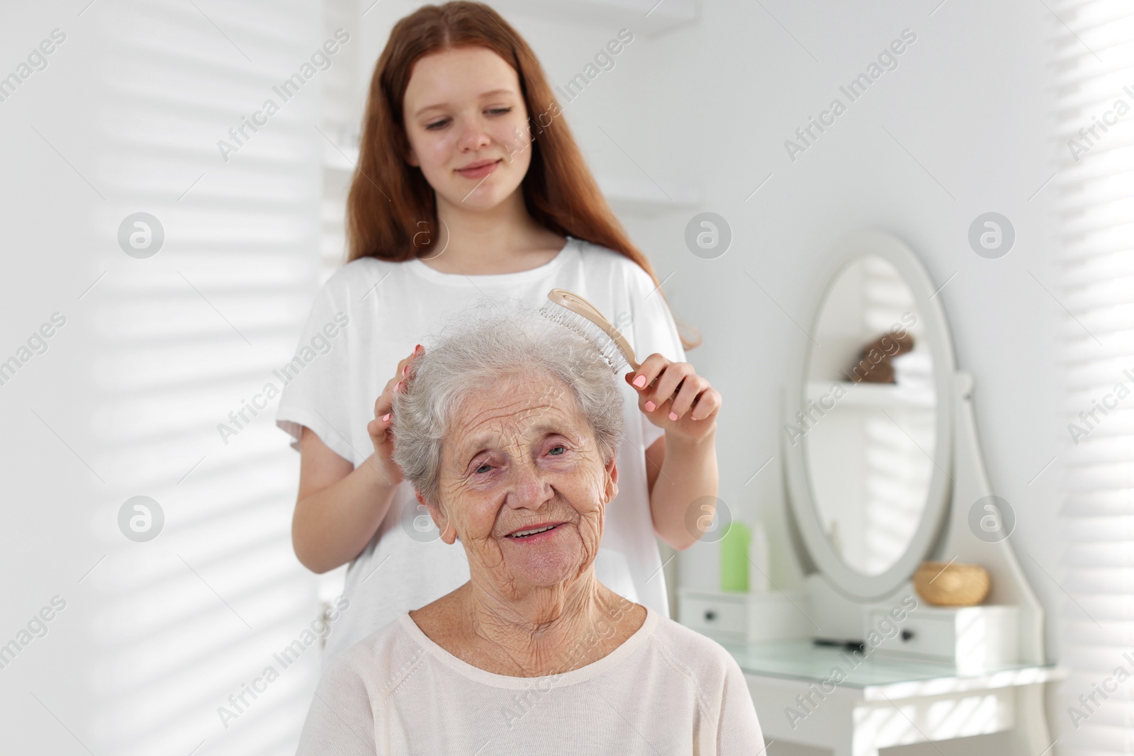 Photo of Granddaughter brushing her grandmother with brush at home