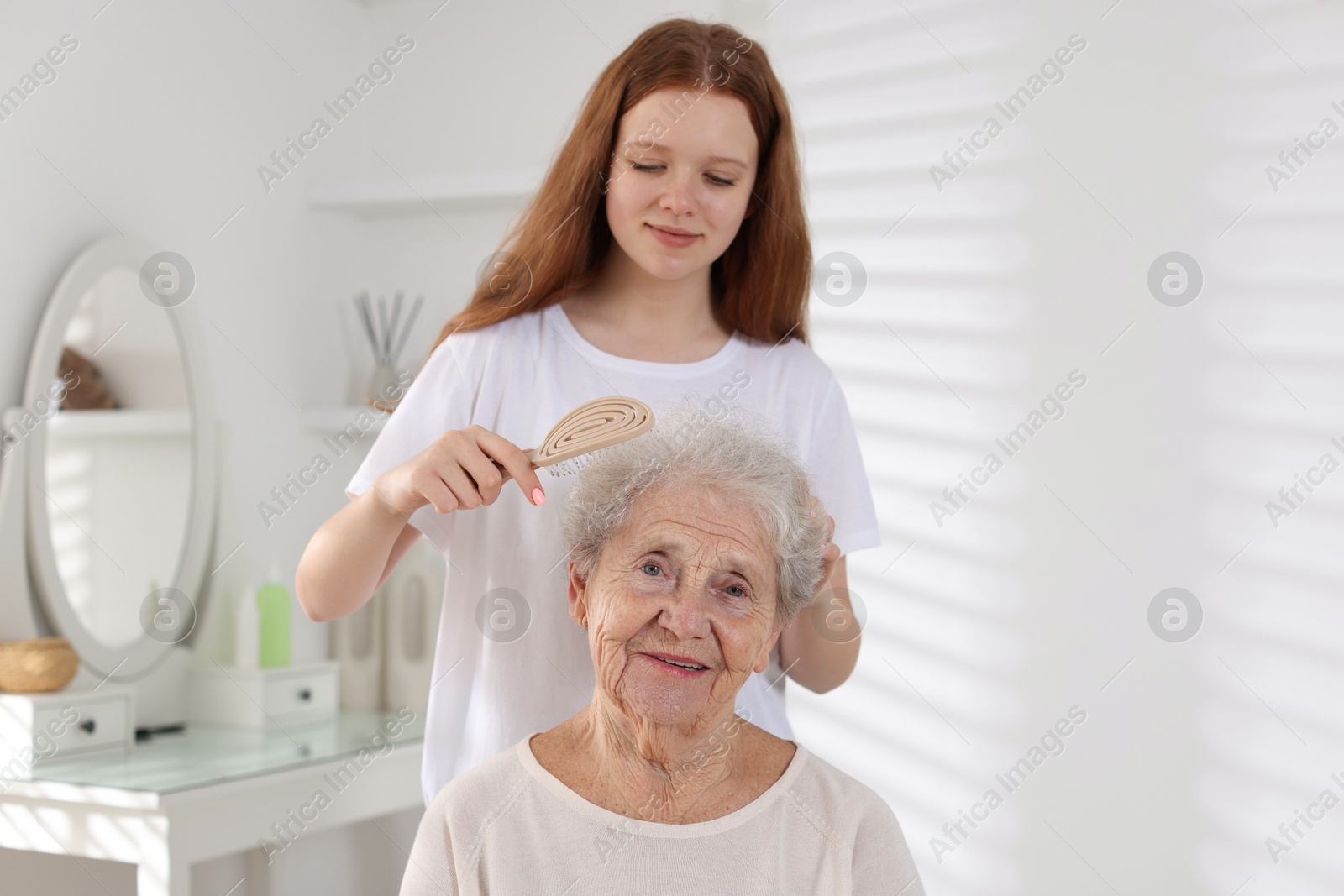 Photo of Granddaughter brushing her grandmother with brush at home