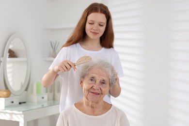 Photo of Granddaughter brushing her grandmother with brush at home