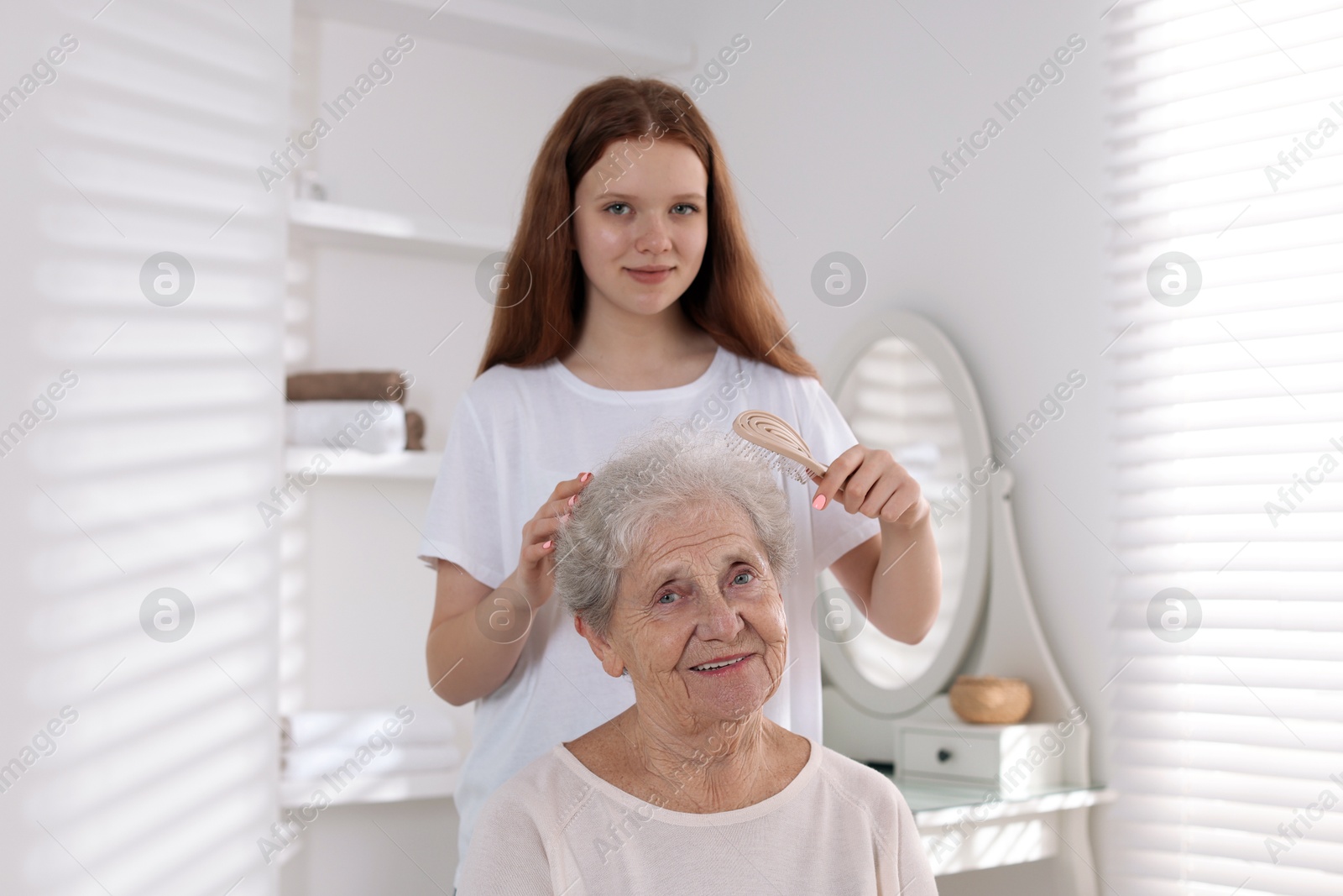 Photo of Granddaughter brushing her grandmother with brush at home