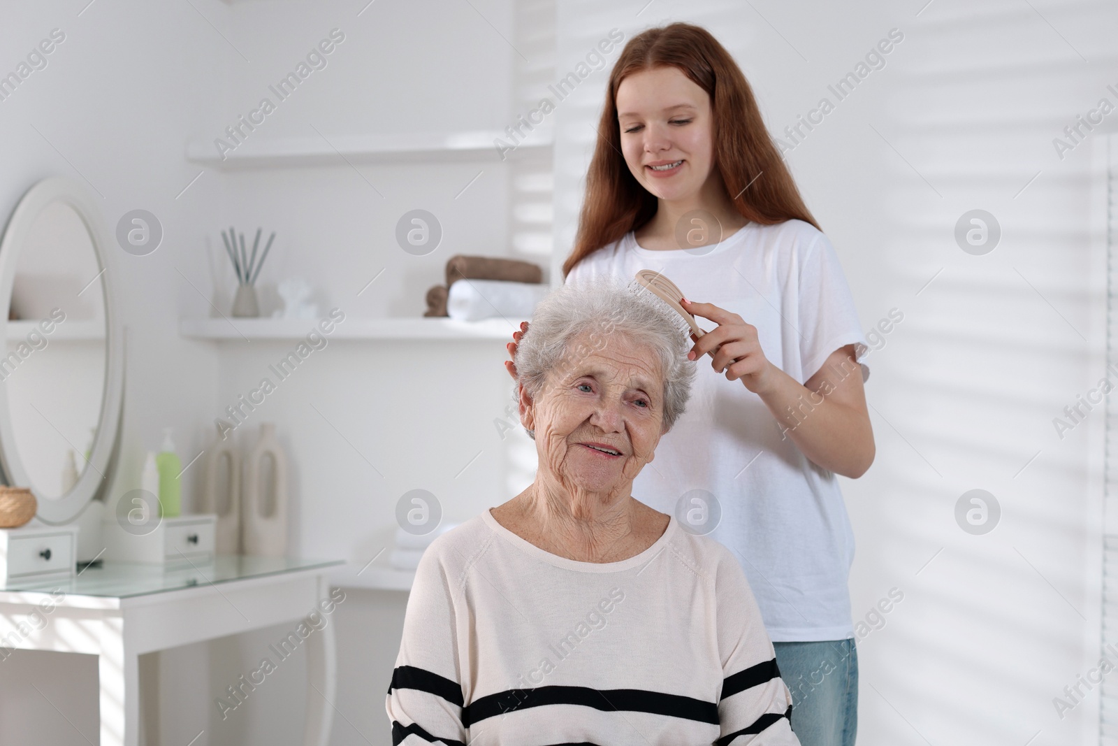 Photo of Granddaughter brushing her grandmother with brush at home