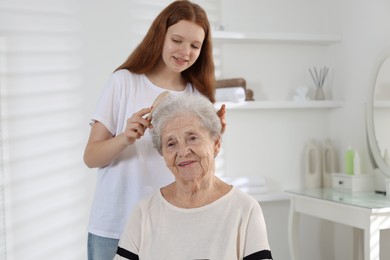 Photo of Granddaughter brushing her grandmother with brush at home