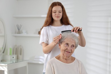 Photo of Granddaughter brushing her grandmother with comb at home