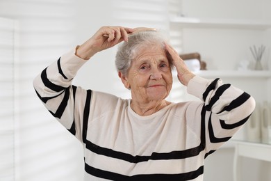 Photo of Senior woman brushing her hair with brush at home