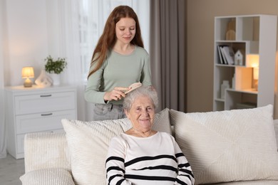 Photo of Granddaughter brushing her grandmother with brush at home