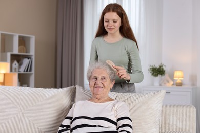 Photo of Granddaughter brushing her grandmother with brush at home