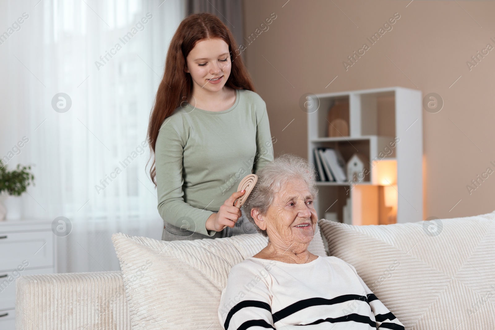 Photo of Granddaughter brushing her grandmother with brush at home