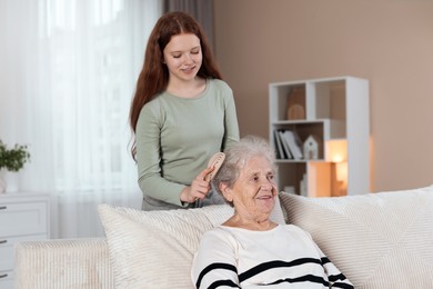 Photo of Granddaughter brushing her grandmother with brush at home