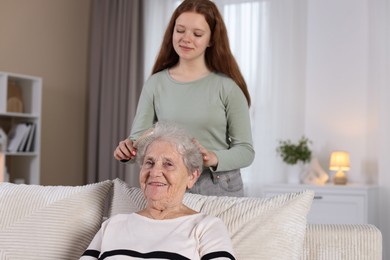 Photo of Granddaughter brushing her grandmother with brush at home