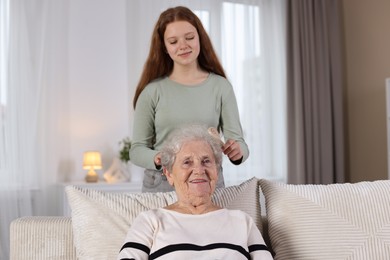 Photo of Granddaughter brushing her grandmother with brush at home