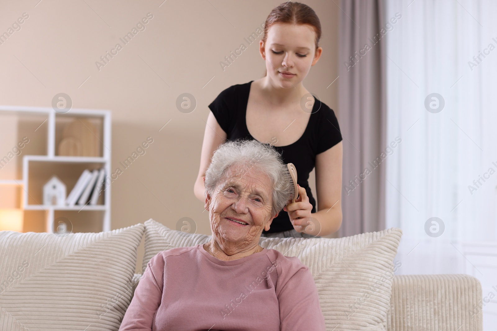 Photo of Granddaughter brushing her grandmother with brush at home