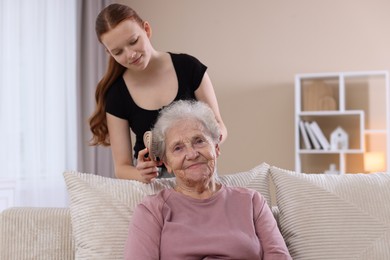 Photo of Granddaughter brushing her grandmother with brush at home