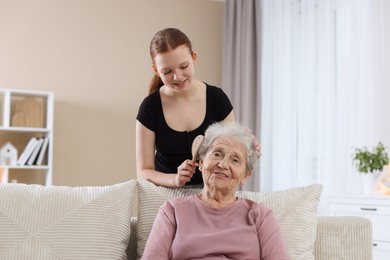 Photo of Granddaughter brushing her grandmother with brush at home