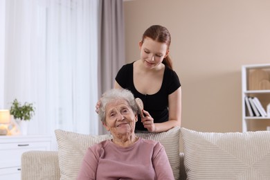 Photo of Granddaughter brushing her grandmother with brush at home