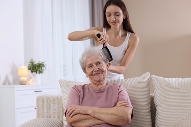 Photo of Woman brushing senior lady with comb indoors