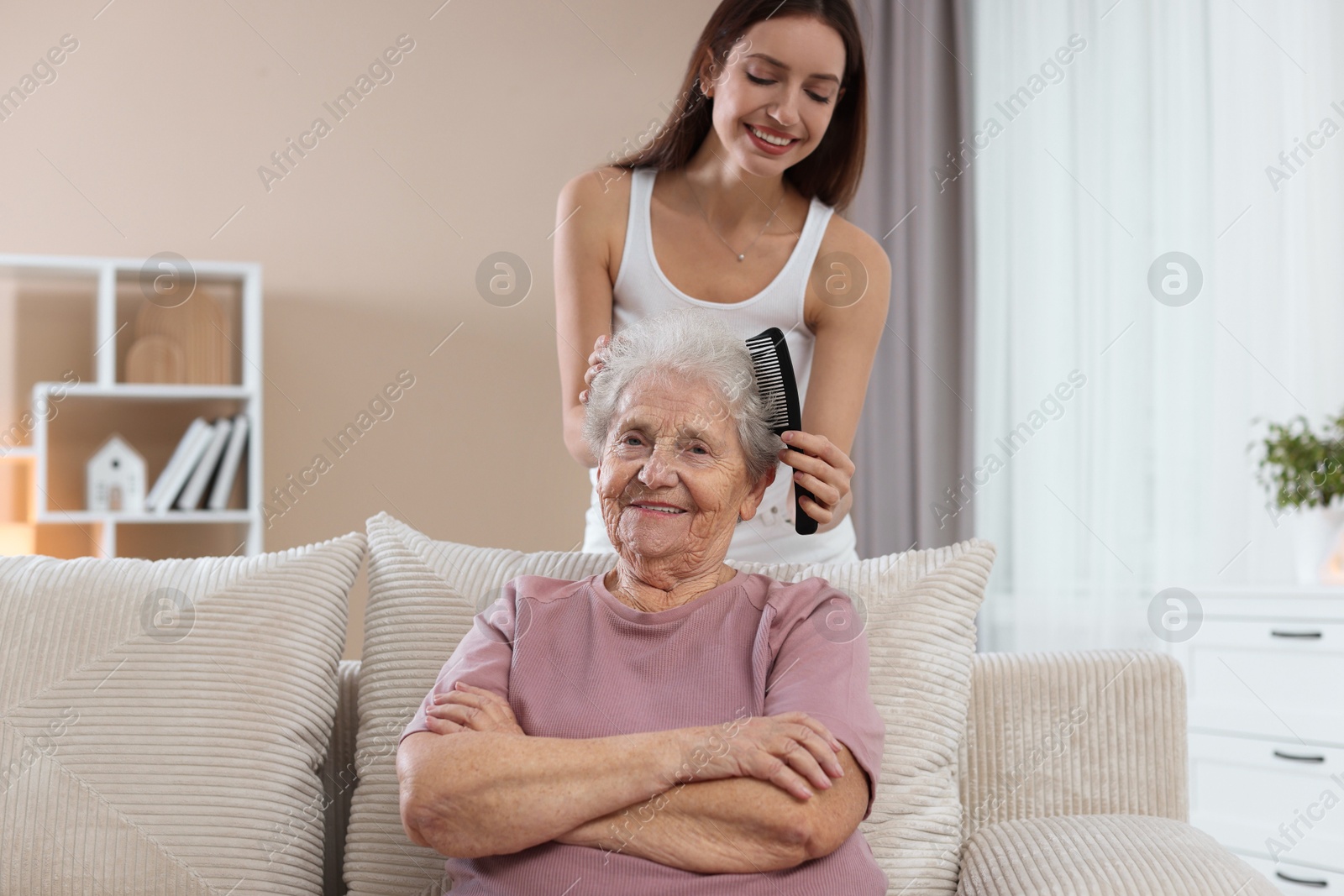 Photo of Woman brushing senior lady with comb indoors