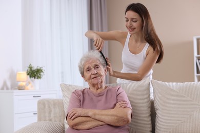 Photo of Woman brushing senior lady with comb indoors