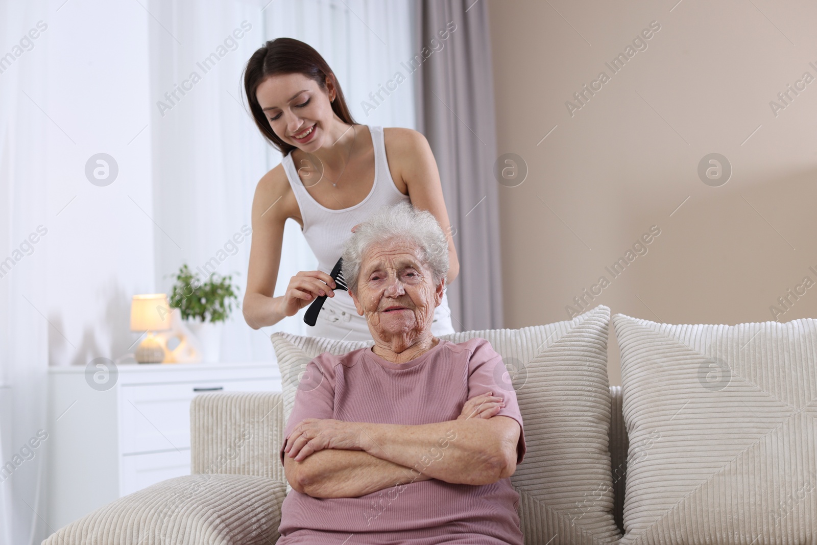 Photo of Woman brushing senior lady with comb indoors