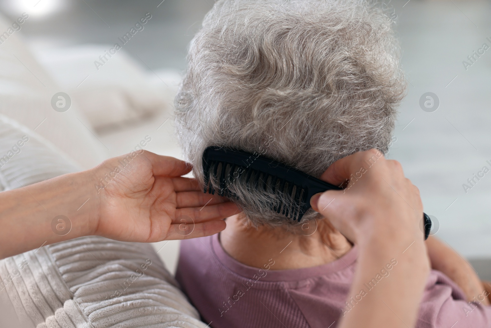 Photo of Woman brushing senior lady with comb indoors, closeup