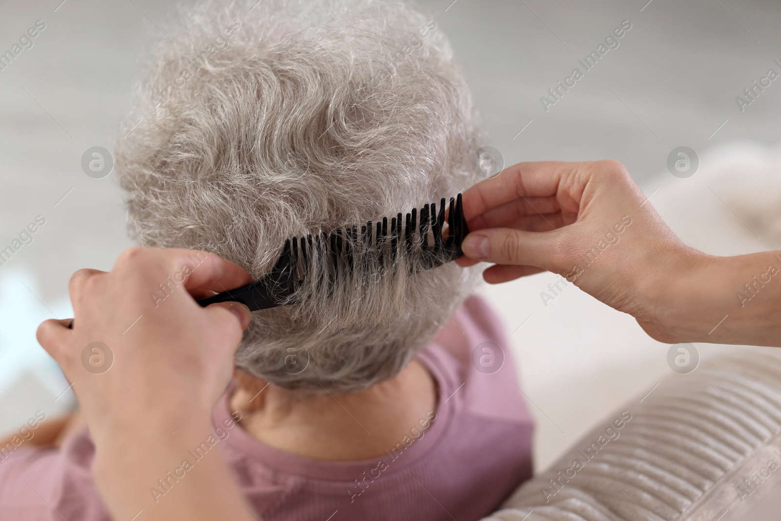 Photo of Woman brushing senior lady with comb indoors, closeup