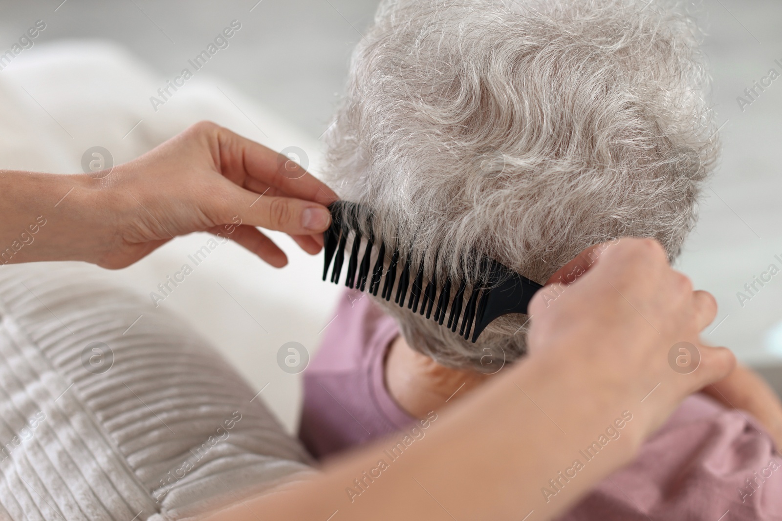 Photo of Woman brushing senior lady with comb indoors, closeup