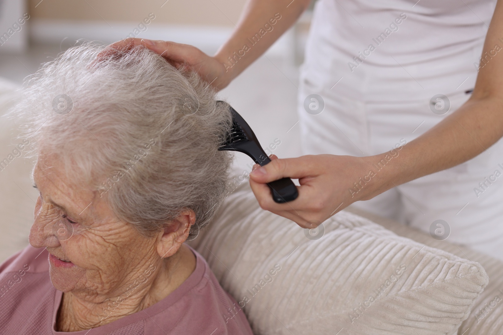 Photo of Woman brushing senior lady with comb indoors, closeup