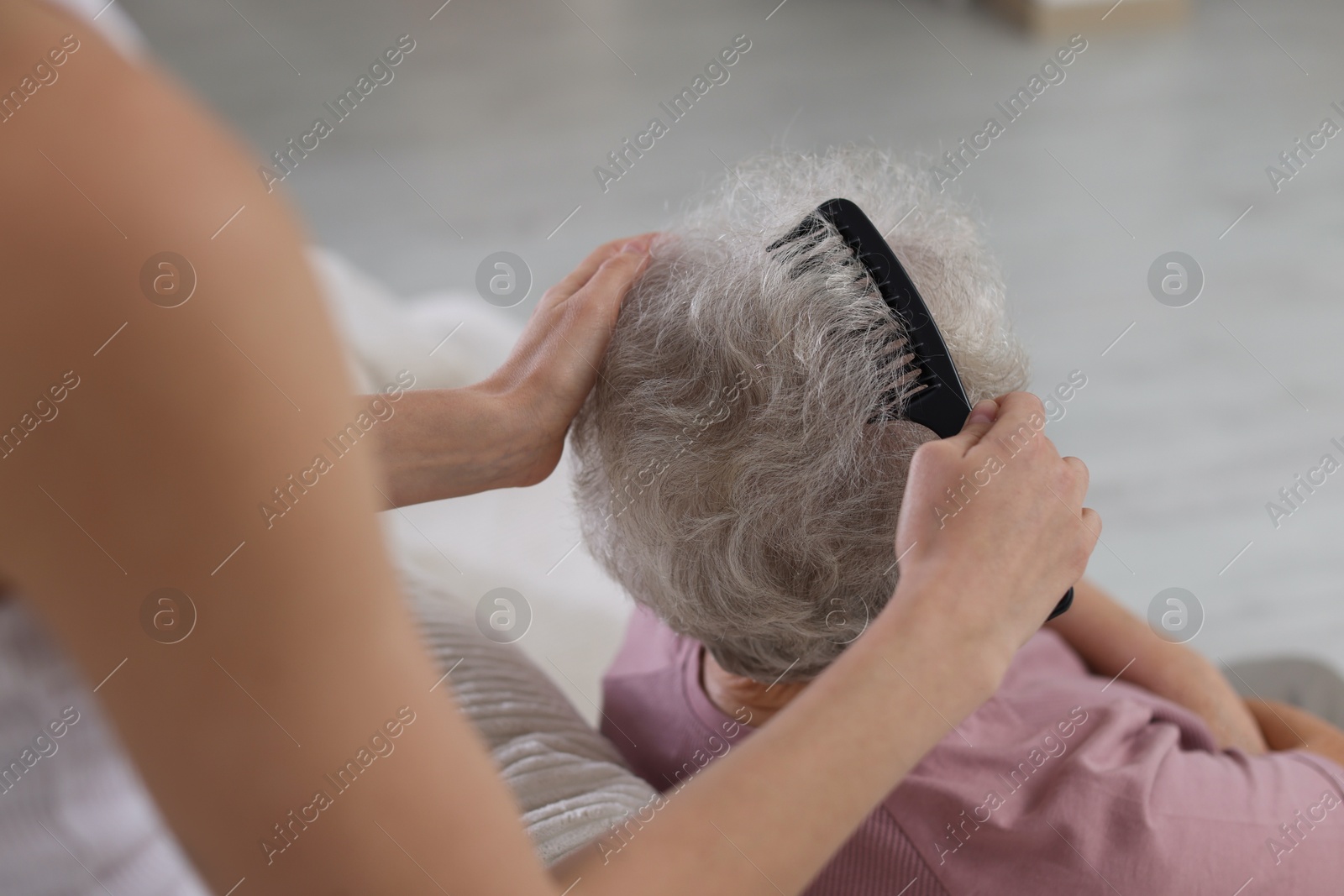 Photo of Woman brushing senior lady with comb indoors, closeup