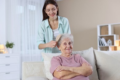 Photo of Woman brushing senior lady with brush indoors