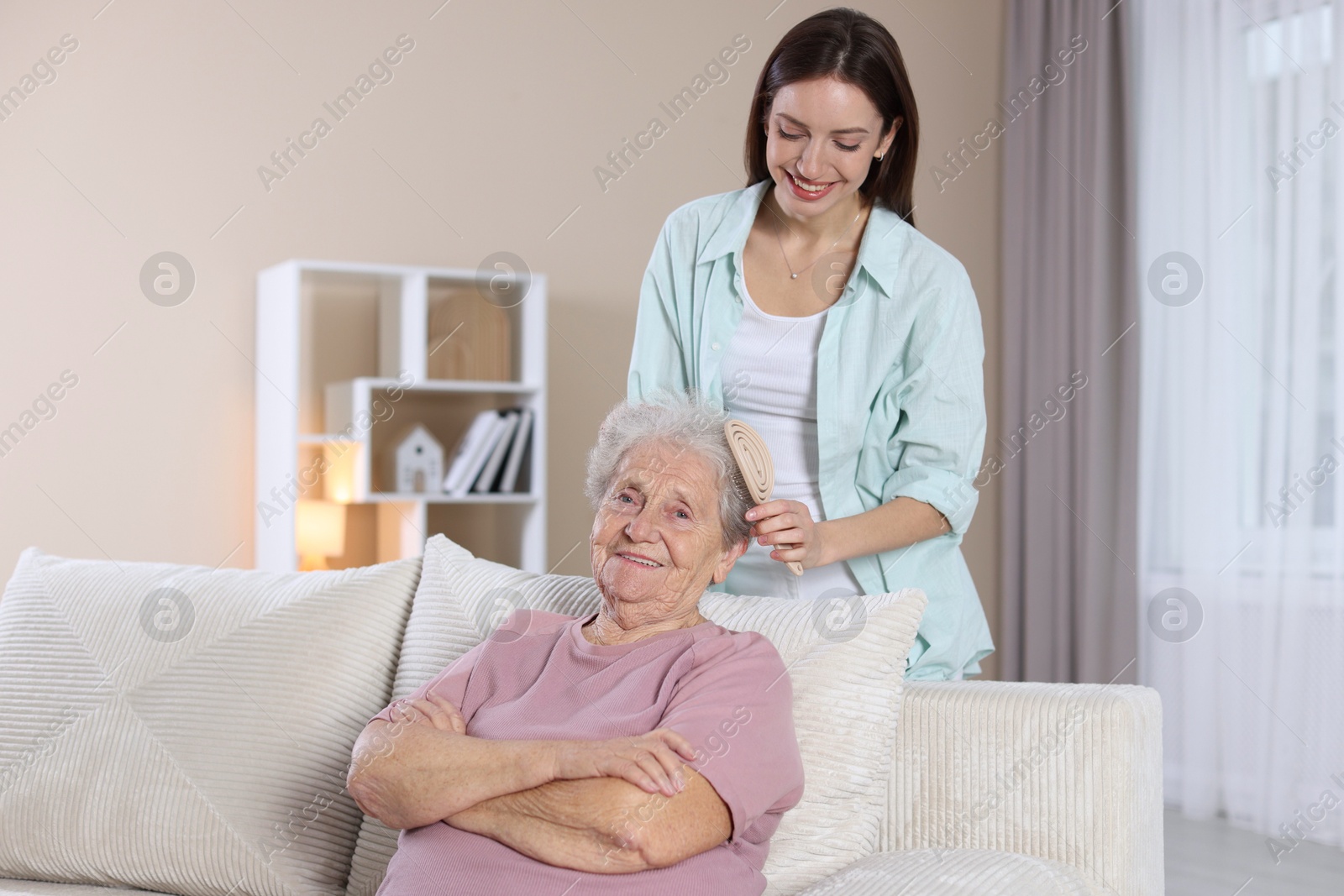 Photo of Woman brushing senior lady with brush indoors