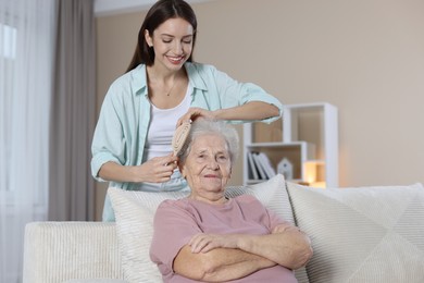 Photo of Woman brushing senior lady with brush indoors