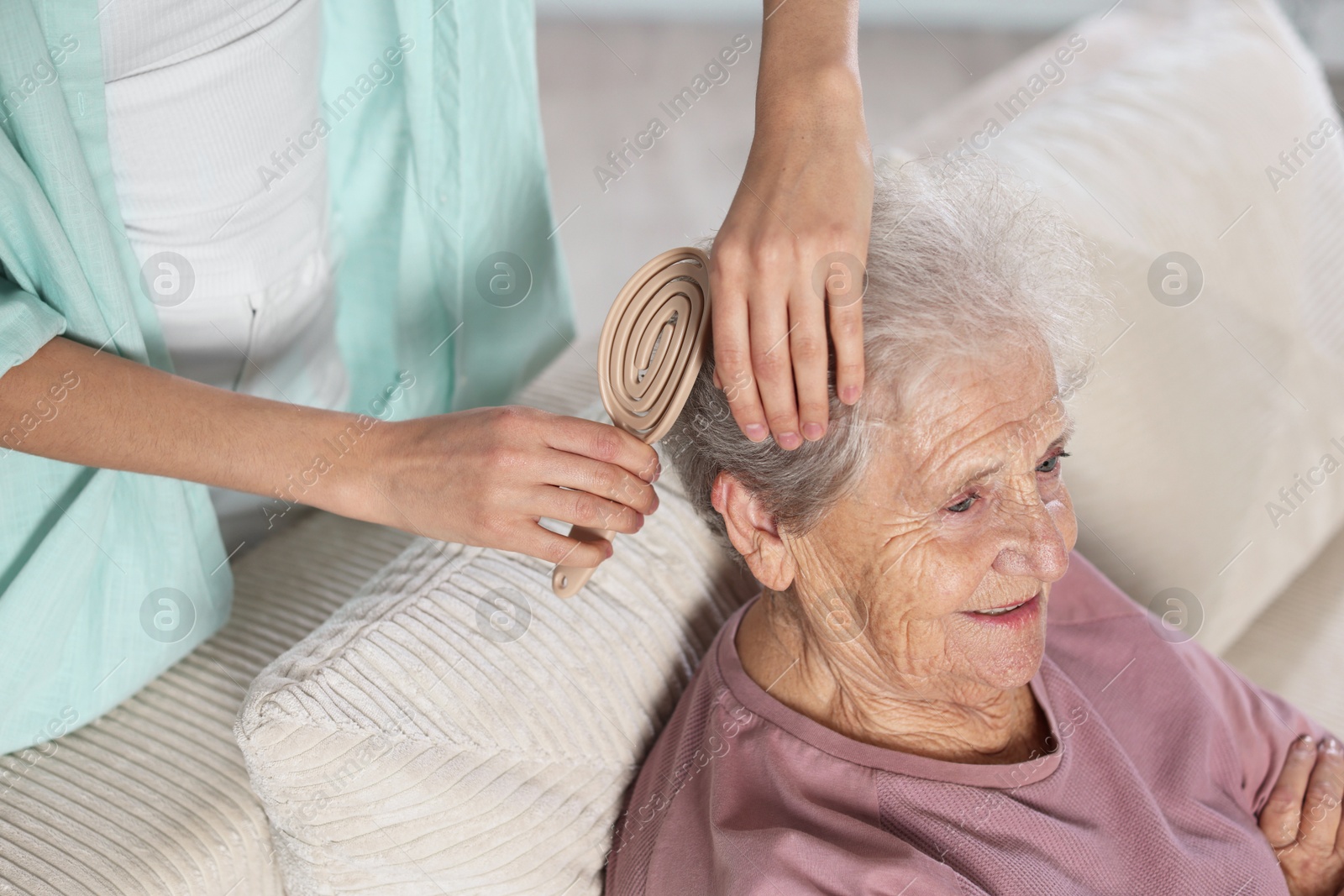 Photo of Woman brushing senior lady with brush indoors, closeup