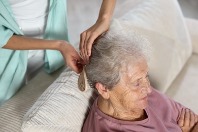 Photo of Woman brushing senior lady with brush indoors, closeup