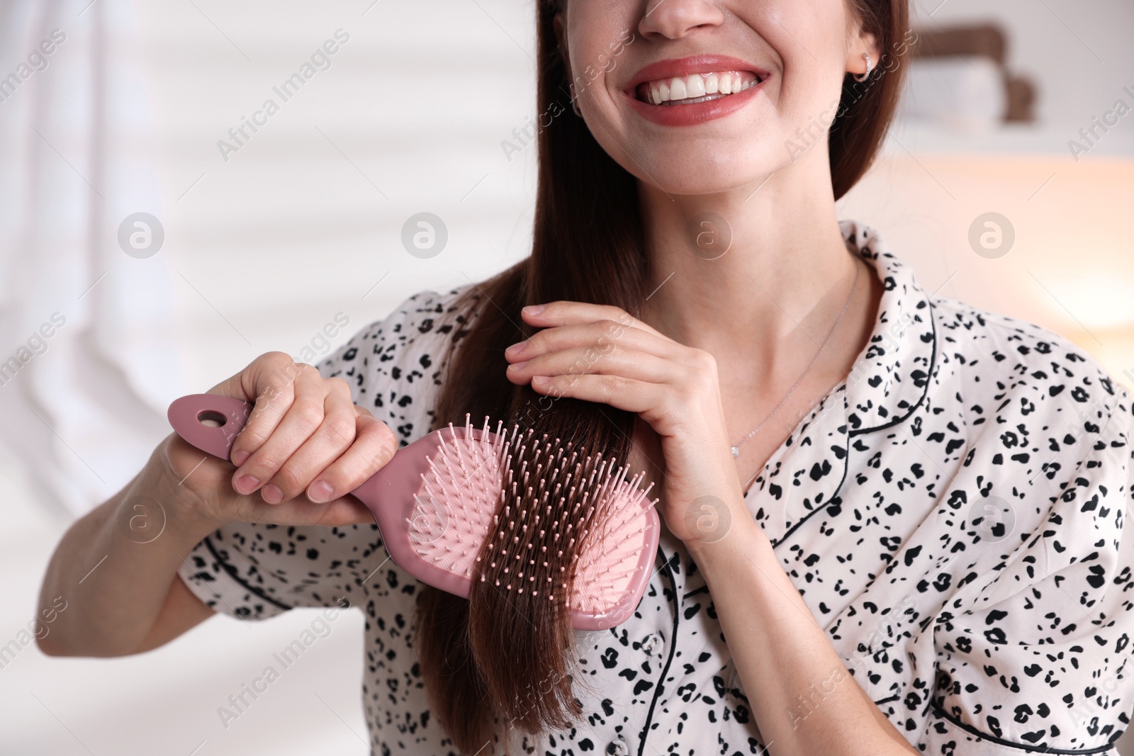 Photo of Woman brushing her hair at home, closeup