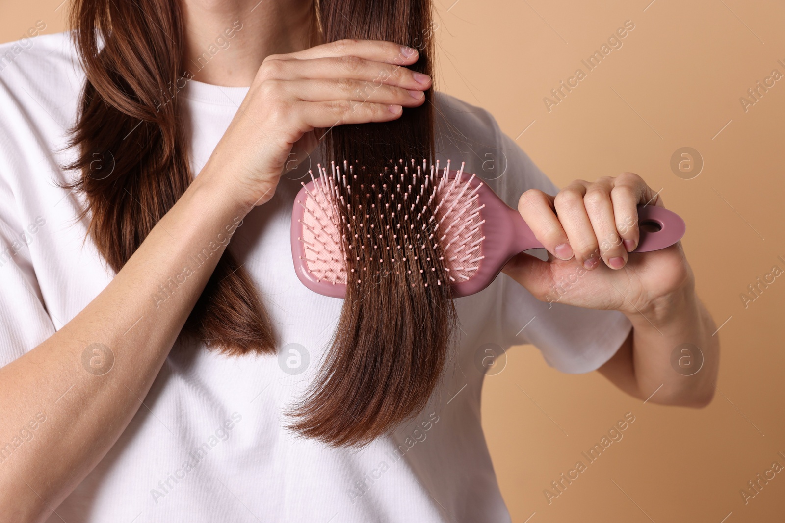 Photo of Woman brushing her hair on beige background, closeup